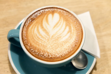 A cup of coffee Latte art green glass on wood table