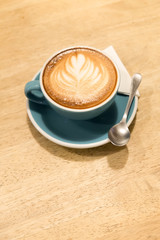 A cup of coffee Latte art green glass on wood table