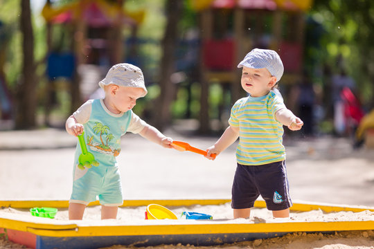 Two baby boys playing with sand