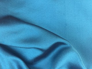 Woven texture of silk fabric or yarn turquois color changeable for background. Draped folded satin. Advertising copy space.