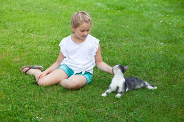 Obraz na płótnie Canvas child sitting on the grass and petting a cat