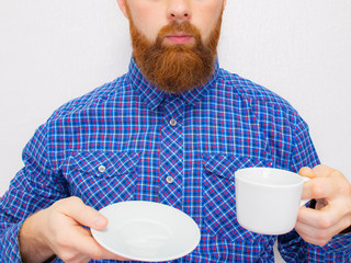 handsome bearded man with stylish hair beard and mustache on serious face in shirt holding white cup or mug with good morning text drinking tea or coffee in studio on grey background