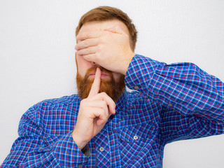 Cropped image of a handsome naked man showing silence gesture with finger over lips isolated over white background.