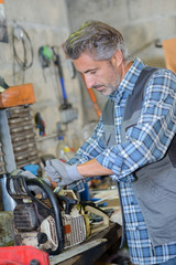 mechanic fixing a chainsaw - obrazy, fototapety, plakaty