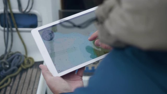 Traveler using digital tablet looking map while sailing on sea ship
