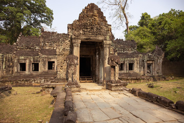 Fototapeta na wymiar Ancient ruins of Preah Khan temple in Angkor Wat, Cambodia. Decorated entrance with stone bas-relief. Stone temple ruin.