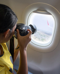A woman take photo a landscape from a window of a flying plane. The passenger with camera photographed from the window of aircraft.