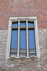 Fototapeta na wymiar Old window surrounded by stones wall and orange bricks