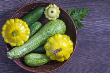 Harvesting. Cucumbers, zucchini, patty pan squashes   in a bowl on an old wooden table.