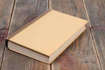 A book in yellow binding on a wooden background. Front view.