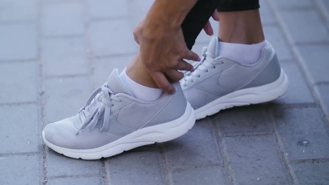 Running sport injury - twisted sprained ankle. Female athlete runner touching foot in pain due to broken ankle.