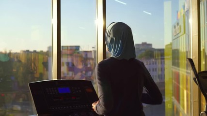 Close up young muslim girl in hijab doing sports on the treadmill