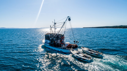 Obraz premium Fishing boat pulling two other smaller fishing boats