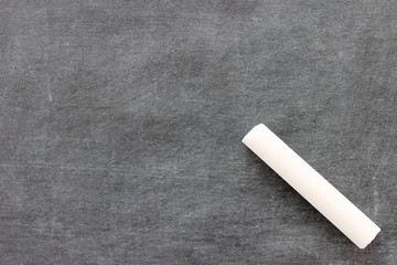 Blank chalkboard surface with piece of white chalk.