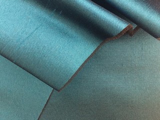 Woven texture of silk fabric or yarn turquois beige color changeable for background. Advertising copy space. Crumbling edge. Draped folded satin.