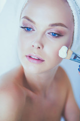 Young beautiful woman making make-up near mirror, in bathroom
