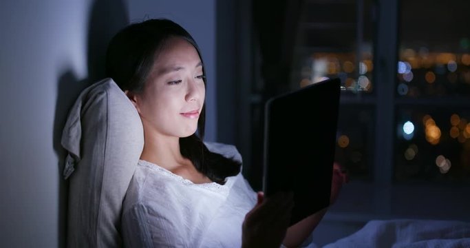 Woman watching on tablet on bed at night