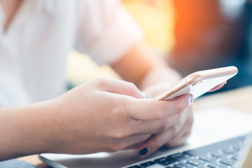 Young woman using smartphone and laptop computer working and business contact at home