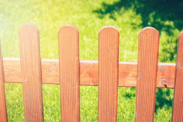 Wooden fence on green grass lawn, on a bright sunny day