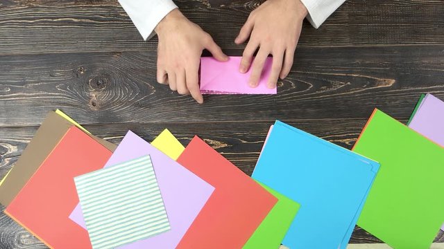 Making origami, top view. Folding pink papper.