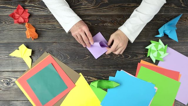 Making origami figure with purple paper. Top view. Colourful paper for origami.