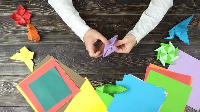 Man hands make purple paper origami. Top view flat lay.
