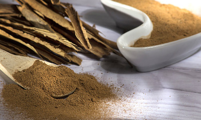 Cinnamon sticks with powder isolated in ceramic bowl on white background