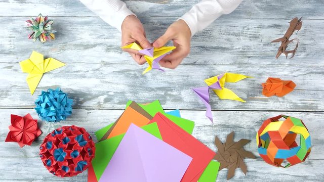 Male hands making origami figure. Top view, flat lay.