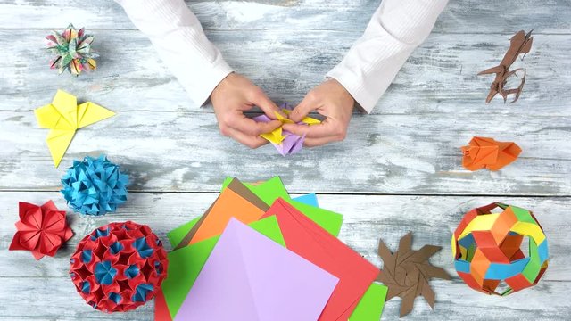 Making colourful origami flower. Top view, flat lay. Wooden table background.