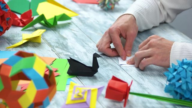 Creating white paper swan. Folding paper, origami art, close up.