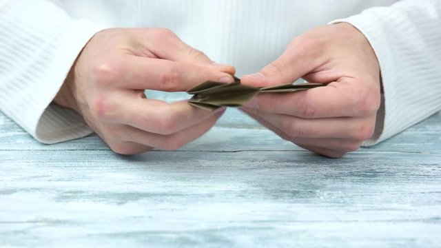 Hands making brown origami shape, close up. Male caucasian hands.
