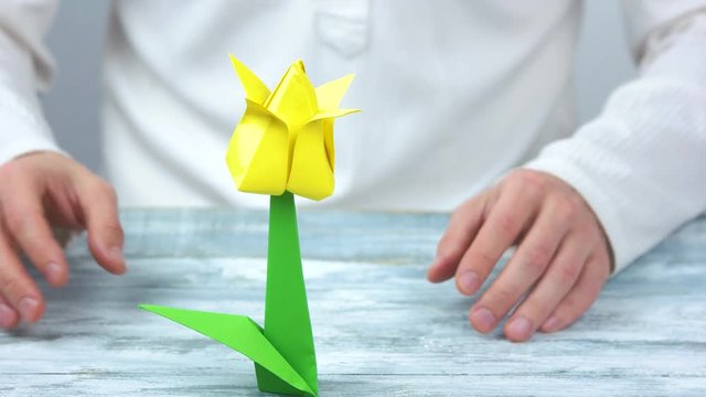 Man making yellow origami flower. Close up. Yellow tulip.