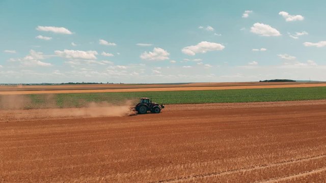 Aerial drone view of red tracor working in wheat field. Agriculture and environment in European Union.