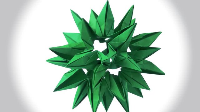 Green origami transforming spiky ball. Amazing rotating figure. White isolated background.