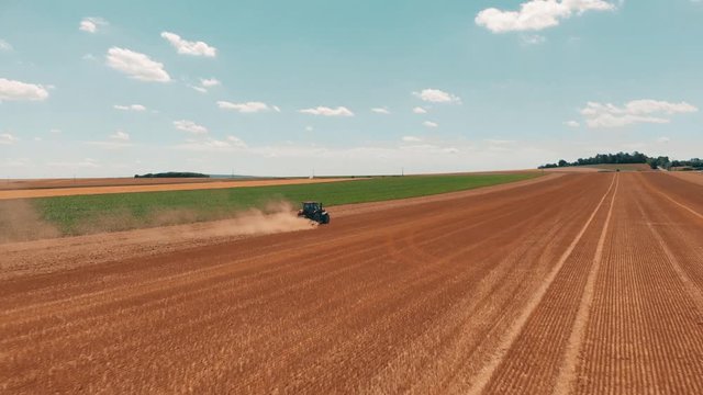 Aerial drone view of red tracor working in wheat field. Agriculture and environment in European Union.