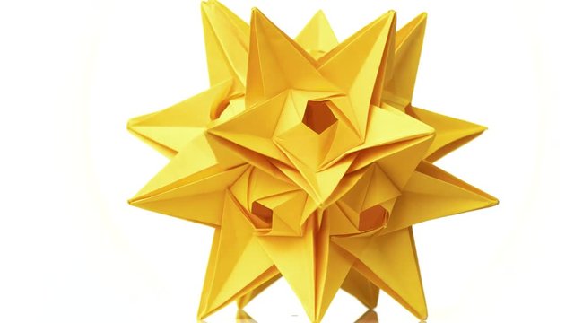 Yellow origami transforming spiky ball. Beautiful rotating origami figure. White isolated background.