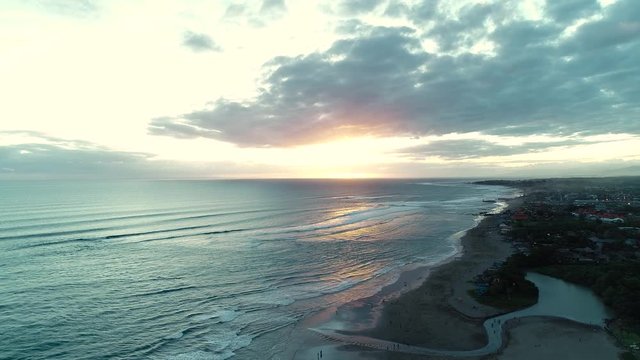 Sunset on the black sand beach, Indonesia, Bali. Aerial view. 4K