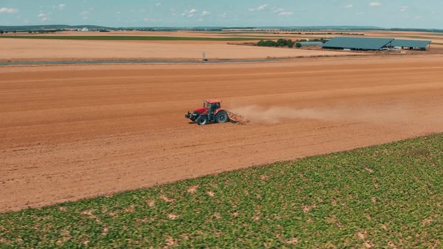 Aerial drone view of red tracor working in wheat field. Agriculture and environment in European Union.