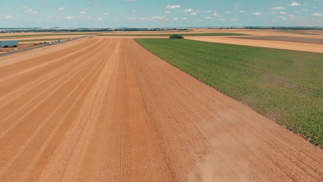 Aerial drone view of red tracor working in wheat field. Agriculture and environment in European Union.