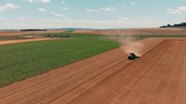 Aerial drone view of red tracor working in wheat field. Agriculture and environment in European Union.