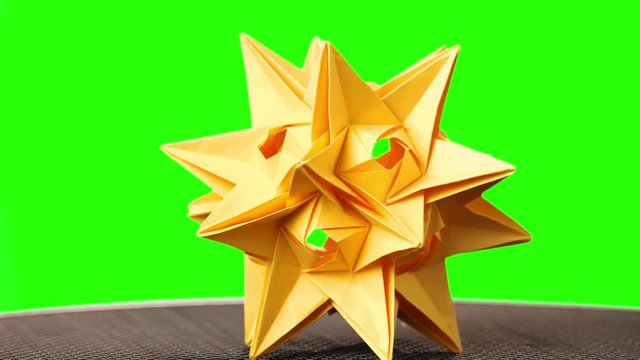 Yellow origami spiky ball exhibition. Green hromakey background for keying.