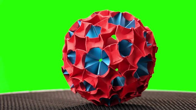 Red and blue origami magic ball. Green hromakey background for keying.