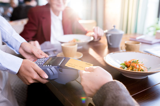Hand of customer paying with contactless credit card with NFC technology at the restaurant
