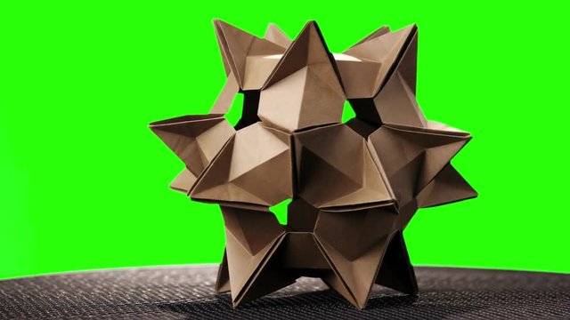 Yellow origami transforming spiky ball. Green hromakey background for keying.