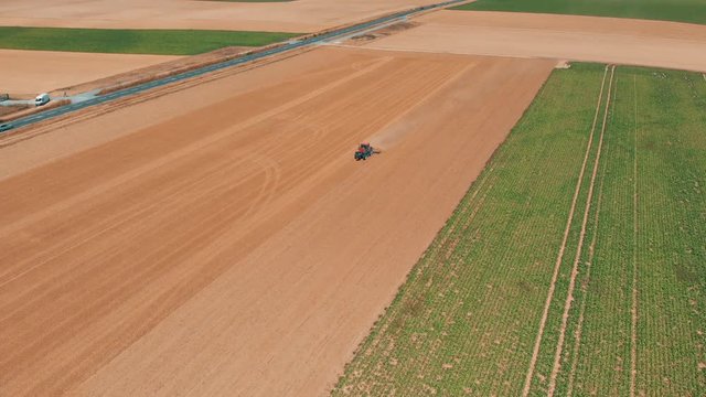 Aerial drone view of red tracor working in wheat field. Agriculture and environment in European Union.