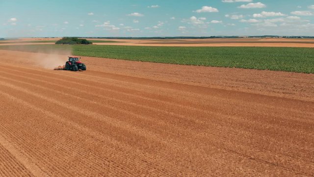 Aerial drone view of red tracor working in wheat field. Agriculture and environment in European Union.