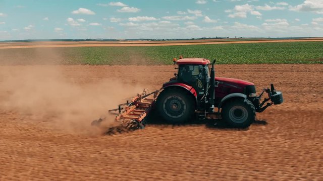 Aerial drone view of red tracor working in wheat field. Agriculture and environment in European Union.