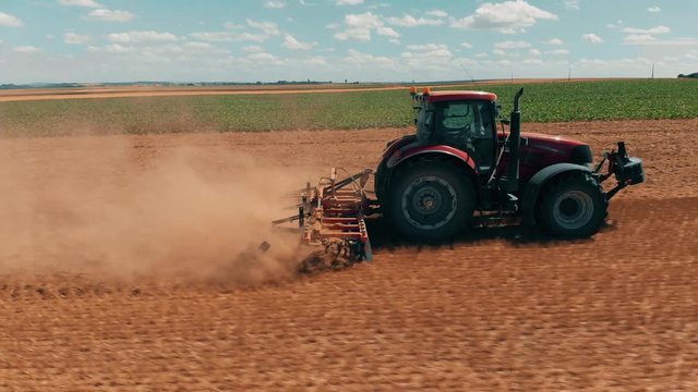 Aerial drone view of red tracor working in wheat field. Agriculture and environment in European Union.