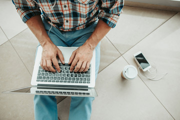 Top view close up male hands typing in notebook computer while listening music