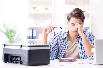 Young man employee working at copying machine in the office 